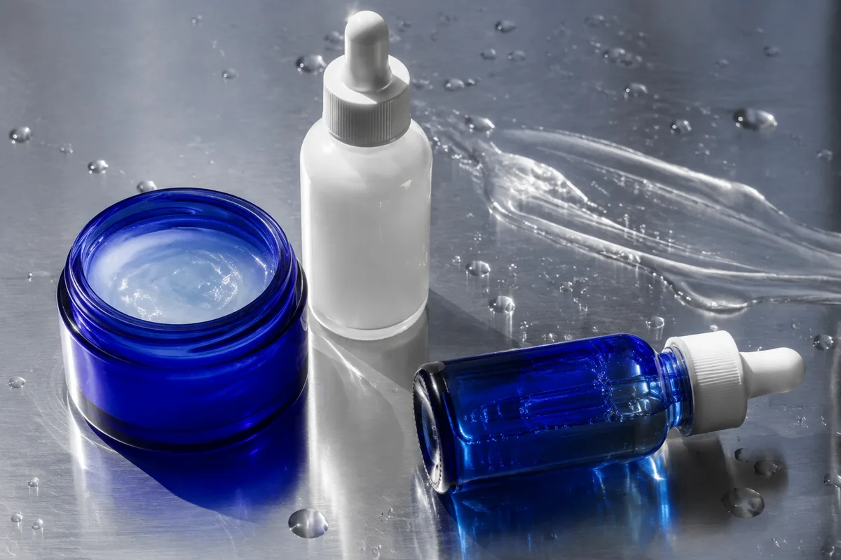 Unbranded cobalt and white skincare containers on steel in sunlight